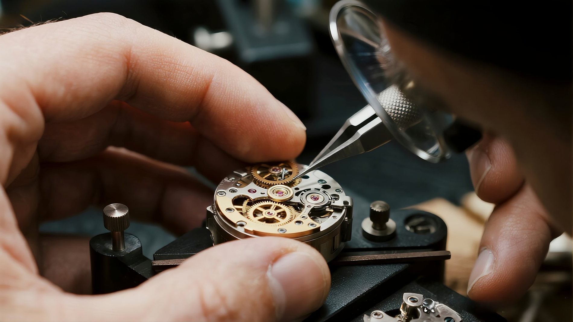 A watchmaker adjusting a fine mechanical movement with tweezers